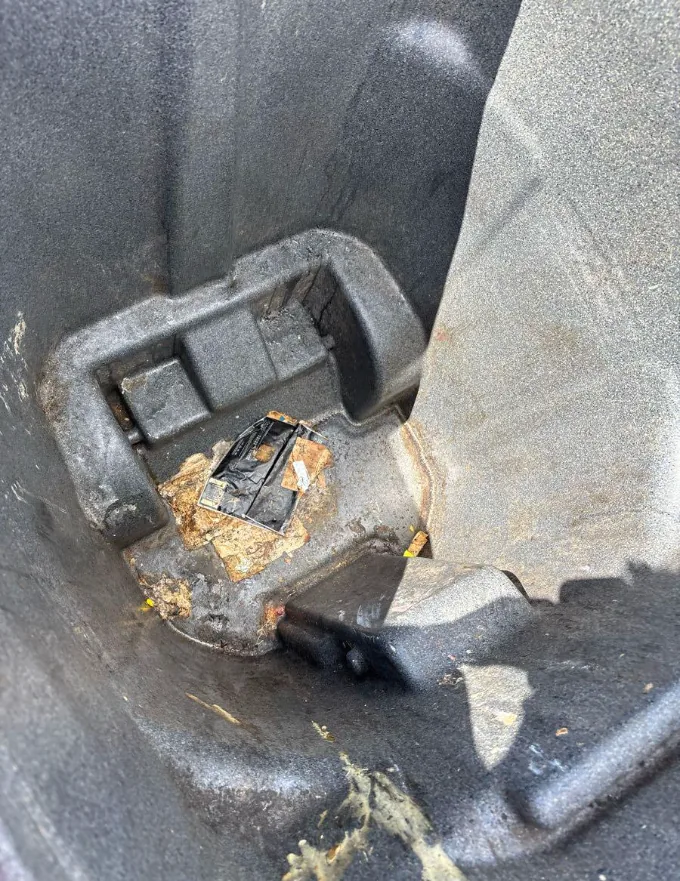 Rust-coloured staining and a stuck-on label baked into the base of a grey cart