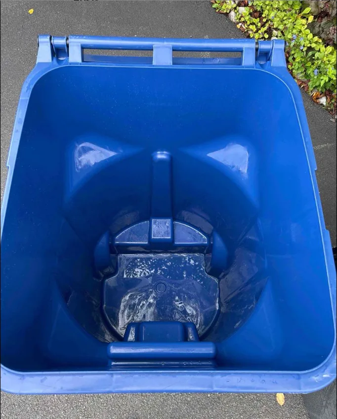 The same blue recycling cart after cleaning, with the streaks and grime washed away